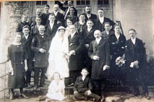 Das Foto zeigt eine Hochzeitsgesellschaft im Jahr 1925. Im Hintergrund ist der Druschma zu sehen.